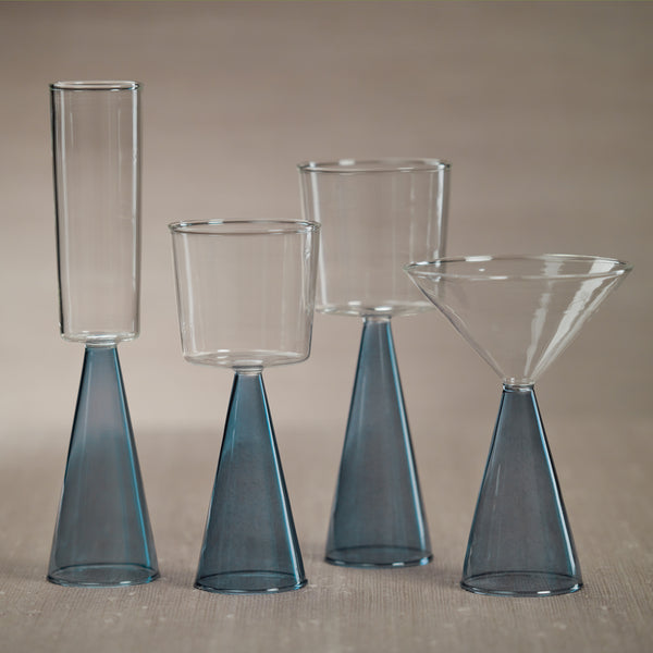 Set of four glass drinkware with blue stems on a beige background