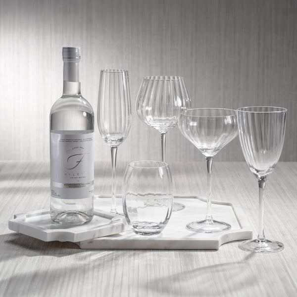 Set of wine glasses and a bottle on a marble tray with a neutral background