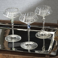 Three clear glass goblets on a reflective surface with a neutral background