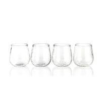 Four clear stemless wine glasses on a white background
