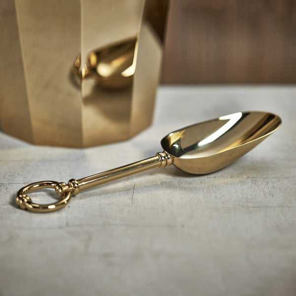 Gold ice scoop on a textured surface with a blurred background