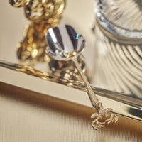 Gold ice scoop with decorative gold stags head handle on a reflective surface