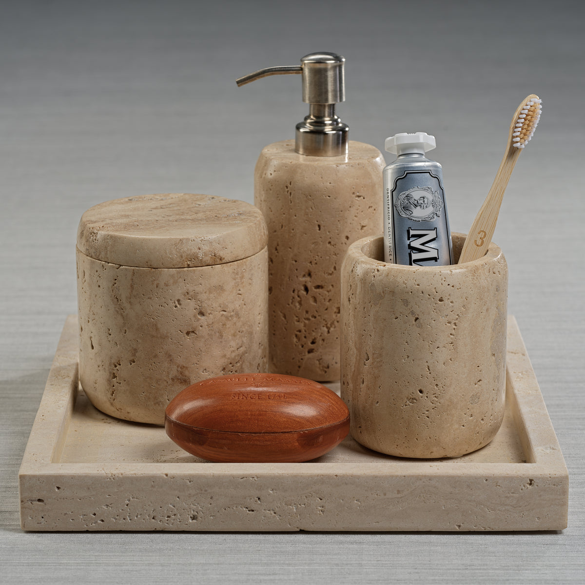 Bathroom set with stone-textured containers on a tray, including a soap dispenser, toothbrush holder, and other items.