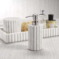 White ribbed soap dispenser with a pump on a bathroom counter.