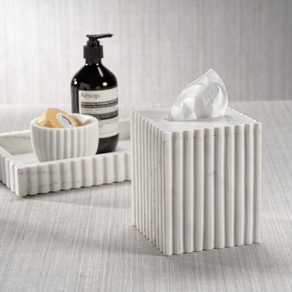 White ribbed tissue box with Aesop bottle and soap dish on a textured surface