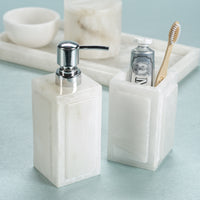 Marble-textured soap dispenser and toothbrush holder on a light blue surface