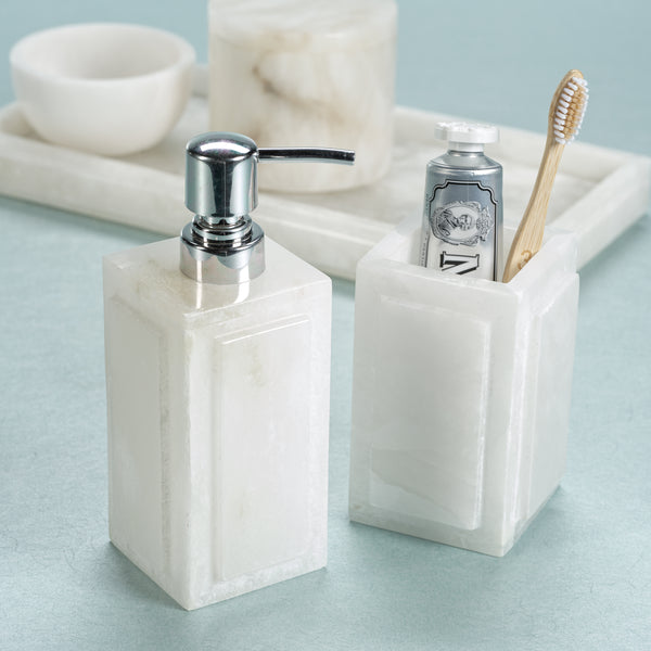 Marble-textured soap dispenser and toothbrush holder on a light blue surface