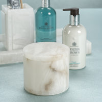 Marble-textured container and bottles with 'Molton Brown' branding on a light blue surface.