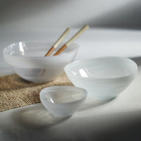 Set of white ceramic bowls on a textured surface with a neutral background