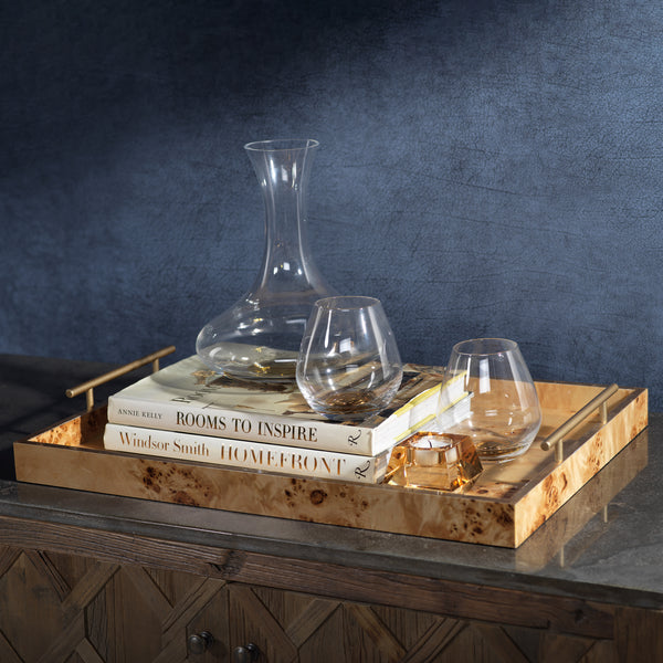 Wooden tray with decanter, glasses, and books against a dark background